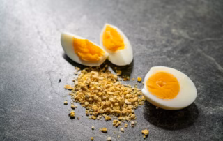 Eifutter für Wellensittiche – Anwendung, Inhaltsstoffe & Dosierung erklärt 9 Eifutter für Wellensittiche – Pulver mit zwei halben Eiern auf grauer Fläche